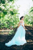 brunette meisje in een turquoise jurk in de lentetuin foto