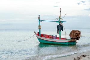 kleine traditionele vissersboot drijvend in de zee aan de kust met kalm oppervlak foto