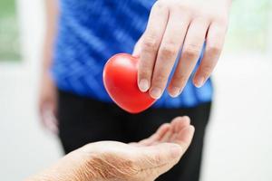 Aziatisch jong jongen geven rood hart naar oud grootmoeder met liefde en zorg. foto