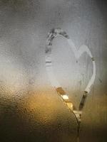 een liefde hart geschilderd Aan een beneveld glas venster achtergrond foto