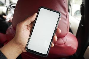 hand met slimme telefoon met leeg scherm in een auto foto