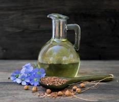 fles van vlas olie met bloemen en zaden foto