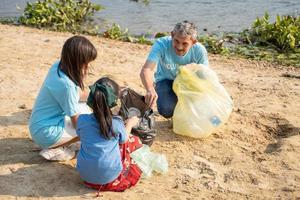gelukkig vrijwilliger Aziatisch en kinderen zijn verzamelen plastic flessen in vuilnis doos naar verminderen globaal opwarming en milieu vervuiling. vrijwilligerswerk en recycling concept. foto