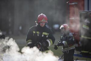brandweerlieden blussen een brand. een team van brandweerlieden Aan een achtergrond van rook en een brand motor foto