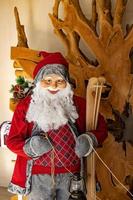decoratie de kerstman claus gekleed in rood met skis Aan een bruin achtergrond foto