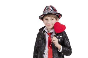 grappig kind in een elegant hoed houdt een hart. jongen met een valentijn. foto