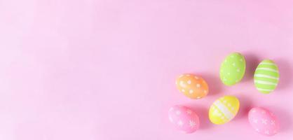gelukkig Pasen vakantie groet kaart concept. kleurrijk Pasen eieren en voorjaar bloemen Aan pastel roze achtergrond. vlak leggen, top visie, kopiëren ruimte. foto