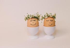 twee eieren met bloemen Aan hun hoofden zijn versierd met bloemen en de woorden 'Vrolijk Pasen' foto