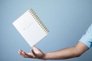 blanco kladblok zweven over- zakenman hand- Aan licht blauw achtergrond, kopiëren ruimte voor uw tekst foto