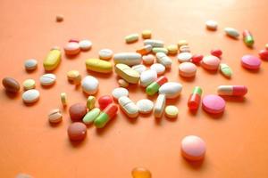 close-up van vele kleurrijke pillen en capsules morsen op oranje achtergrond
