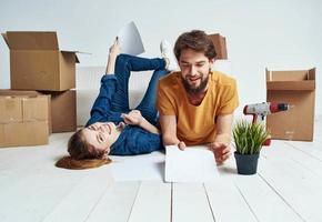 emotioneel Mens en vrouw met karton dozen Aan de verdieping hebben pret in beweging vernieuwing werk foto