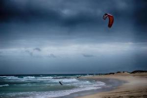 zomer landschap met de oceaan met donker bewolkt golven en surfermi uitrusting met parachutes drijvend Aan de kust foto