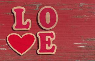 woord liefde gemaakt van houten brieven Aan rood haveloos houten achtergrond foto