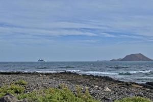 zee landschap met de oceaan en een visie van de Spaans eiland van de lobos met een schip in de achtergrond foto