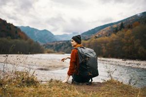 vrouw wandelaar Aan de banken van de rivier- in herfst en bergen in de afstand wolken weer natuur foto