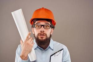 mannetje ingenieur met bril in oranje verf. professioneel blauwdrukken in handen foto