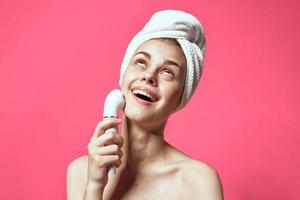 vrouw met handdoek Aan hoofd schoonmaak huid naakt schouders roze achtergrond foto