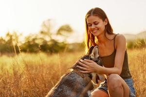 vrouw en haar schor hond gelukkig wandelen en rennen door de gras in de park glimlach met tanden vallen zonsondergang wandelen met huisdier, op reis met een hond vriend foto