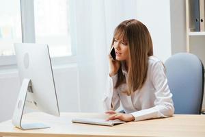 echt aanbiddelijk blond zakenvrouw arbeider maken moeilijk besluit pratend met cliënt in telefoontje in licht modern kantoor. nerveus werknemer werk Aan computer online in ondersteuning onderhoud. kopiëren ruimte foto