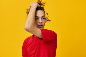 blij grappig Kaukasisch jong Mens in rood t-shirt accenten haar- krullen poseren geïsoleerd Aan over- geel studio achtergrond. de het beste aanbod met vrij plaats voor reclame. emoties voor elke dag concept foto