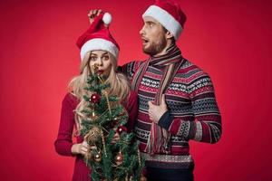 Mens en vrouw Kerstmis boom speelgoed pret vakantie rood achtergrond foto