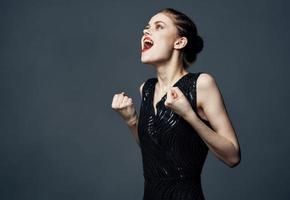 een vrouw in een zwart jurk gebaren met haar handen verrassing genot emoties. foto