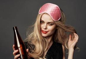 dronken vrouw met een fles van bier helder bedenken blond roze masker voor slaap foto