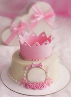 roze taart met kroon en cadeaus in hart doos voor mooi meisje verjaardag partij foto