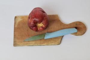 rood jambu bol of Jamaica guava De volgende naar een blauw mes Aan een snijdend bord tegen een wit achtergrond foto