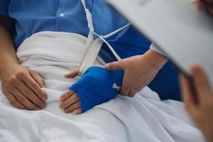 Mens met gebroken arm in gips aan het liegen Aan bed in ziekenhuis. de noodgeval centrum behandeling is gips en blijft hangen met draagdoek voor een verder genezen in een orthopedische kliniek. geduldig pijn van ongeluk blessure. foto