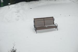 bank in sneeuw. eenzaam winkel in park in winter. leeg ruimte. foto