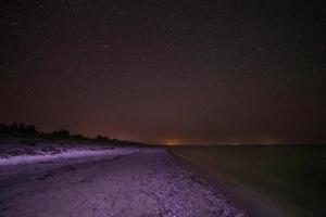 zicht van zanderig strand Bij nacht foto