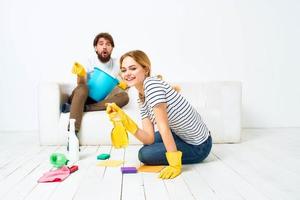 vrouw wast de vloeren een Mens zit Aan de bankstel Bij huis interieur schoonmaak foto