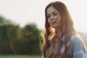 portret van een vrouw met een mooi glimlach en Rechtdoor tanden Aan een zomer dag in de zonsondergang met vliegend gekruld haar- foto