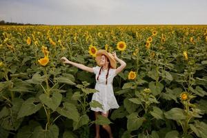 vrouw met vlechten in een wit jurk wandelen Aan een veld- van zonnebloemen ongewijzigd foto