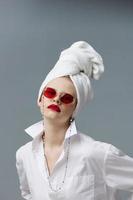 glamoureus vrouw rood zonnebril schoonheidsmiddelen met handdoek Aan hoofd geïsoleerd achtergrond foto