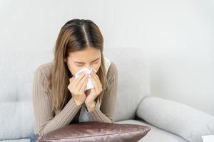 ziek vrouw met een hoofdpijn zittend onder deken, vrouw niezen en vloeibaar neus- met seizoensgebonden influenza, allergisch, hoog koorts en influenza, rusten, virus, coronavirus, voelen ziekte, ademhalings foto