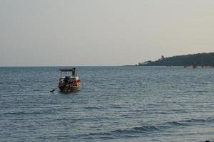 groep van traditioneel lang staart boot drijvend in de zee met zeegezicht en Doorzichtig lucht in achtergrond foto