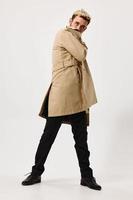 Mens in beige jas mode emoties modern stijl poseren licht achtergrond foto