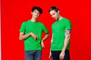 twee vrienden in groen t-shirts zijn staand De volgende naar blik met hun handen emoties foto