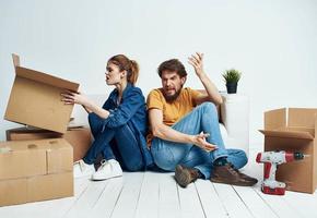 Mens en vrouw Aan de vloeren in een nieuw appartement met dozen en gereedschap voor reparatie foto