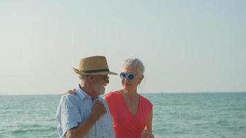 een ouderen paar knuffels hun schouders Bij de strand Aan hun zomer vakantie en ze glimlach en genieten hun vakantie. foto