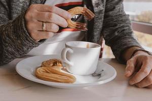 detailopname van een Mens aan het eten een typisch Spaans ontbijt en churros met chocola foto