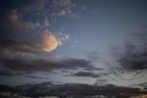 avond blauw lucht met donker wolken lit door de oranje zon foto