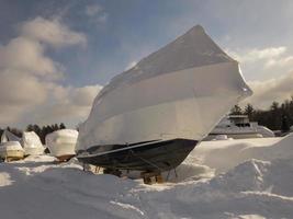 boot zittend Aan blokken gedekt in krimpfolie met andere boten en sneeuw foto