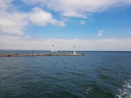 zeegezicht zee met vuurtoren, kalmte water en wit wolken foto