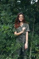 vrouw in Woud lacht en gebaren met haar handen, groen jumpsuit groen bladeren foto