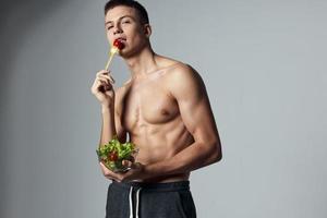 atletisch Mens gespierd torso bord salade gezond voedsel training foto
