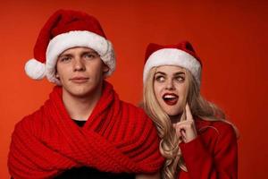 jong paar in de kerstman hoeden pret nieuw jaar vakantie rood achtergrond foto