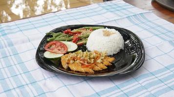 rijst- met kip katsu in zwart bord Aan houten tafel. Indonesisch keuken foto